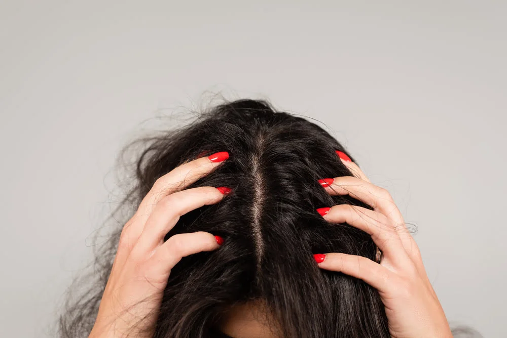 Woman scratching her itchy scalp with red nails